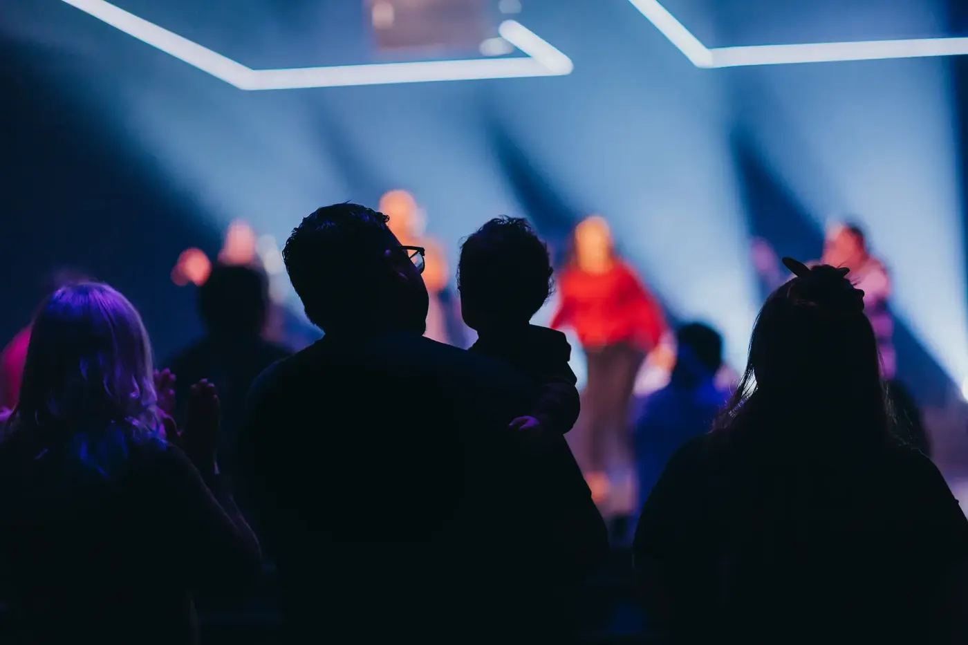 The congregation standing in worship under blue stage lights